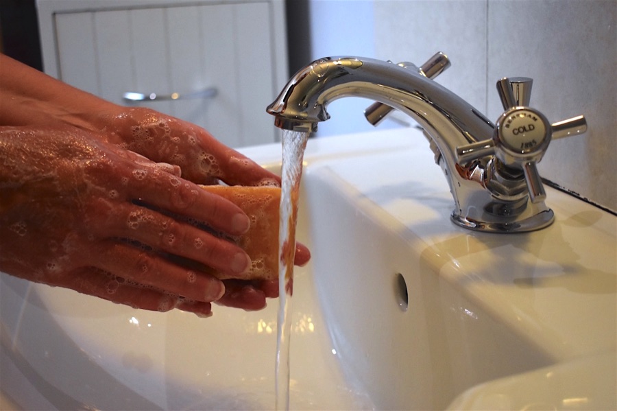 Running tap with hands holding a bar of soap